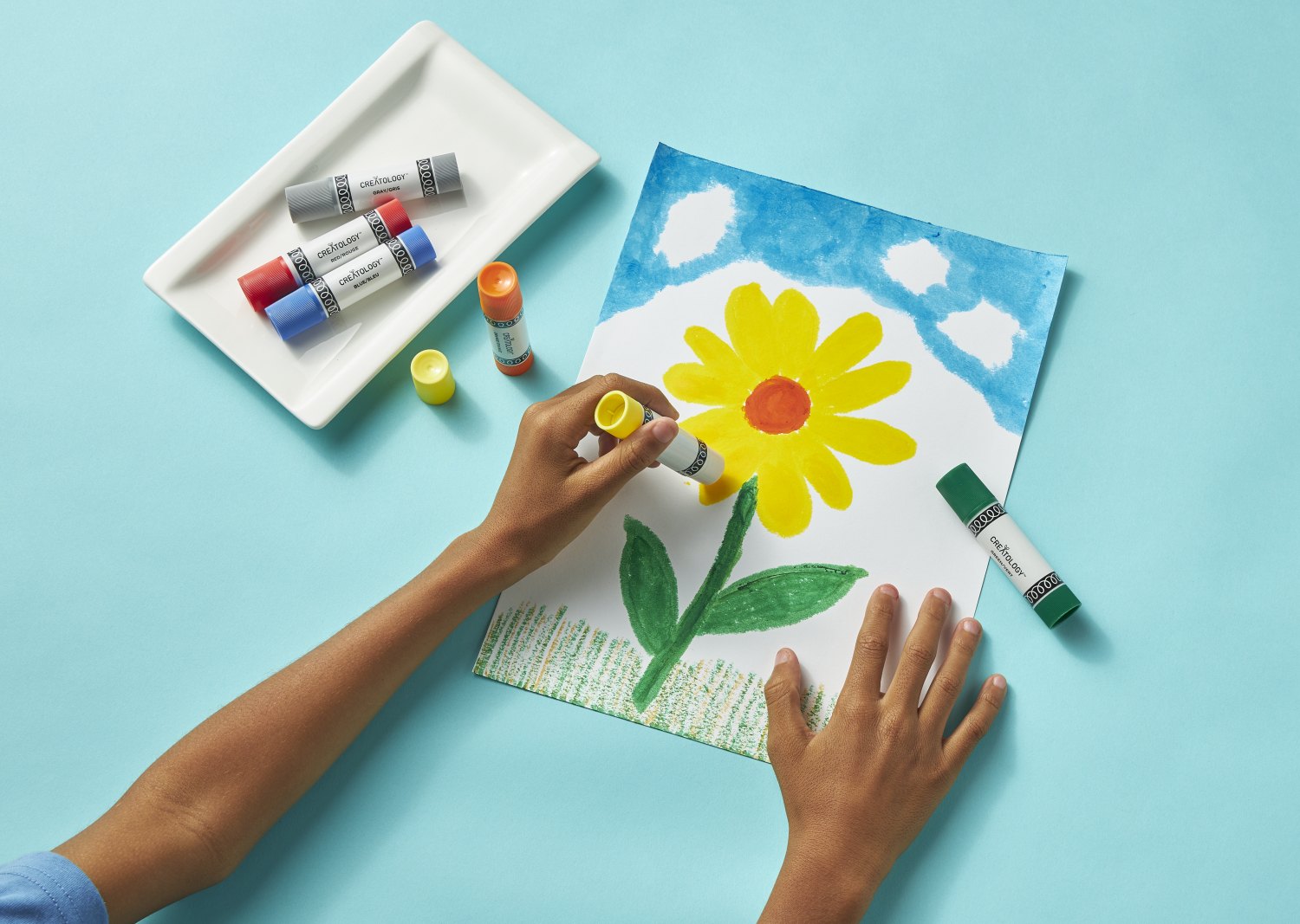 Hands building a paper flower card with Creatology supplies